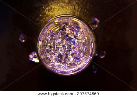 Glass Of Pure Water With Ice Cubes. View From Above. Abstract Dynamic Backdrop For Your Design