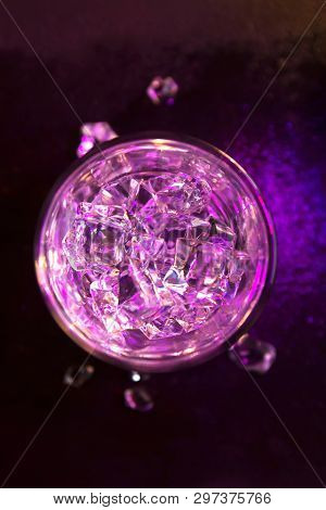 Glass Of Pure Water With Ice Cubes. View From Above. Abstract Dynamic Backdrop For Your Design