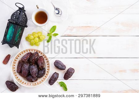 Ramadan Food And Drinks Concept. Ramadan Lantern With Tea, Dates Fruit, Grape And Mint Leaves On A W