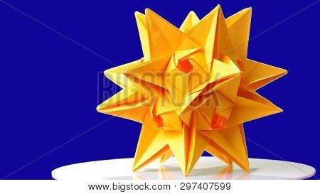 Stellated Dodecahedron Origami On Blue Background. Modular Paper Figurine Made Of Yellow Paper. Star