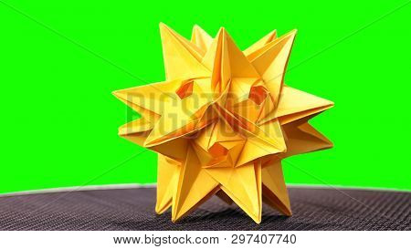 Yellow Star Origami Figurine On Green Background. Stellated Dodecahedron Origami. Modular Paper Star