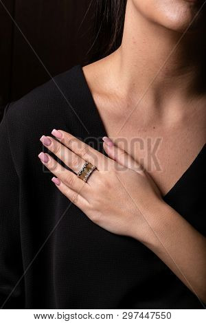 Female Gold Ring With Stones On The Edges On Finger, On A Black Background.