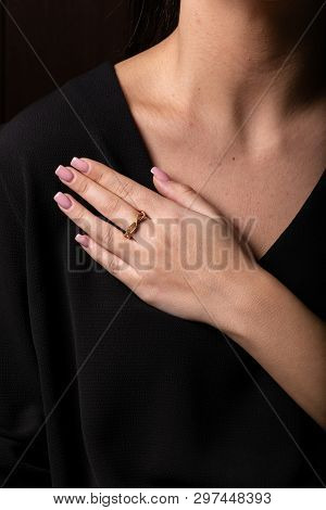 Womens Gold, Twisted The Ring On Her Finger, On Black Background.
