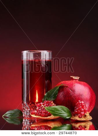 rijpe pomergranate en glas sap op rode achtergrond