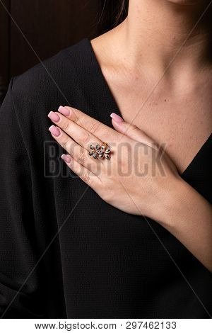 Womens Ring Of Rose Gold In The Form Of A Flower With Black Stones On The Finger, On A Black Backgro