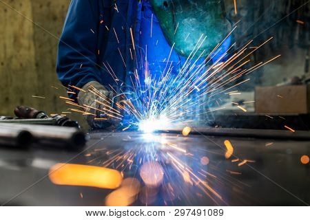 Welder in his workshop welding metal, lots of sparks flying around