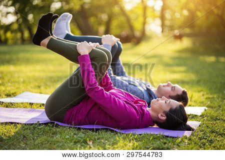 Couple Is Exercising In Park. Exercise For Sciatica Recovery.