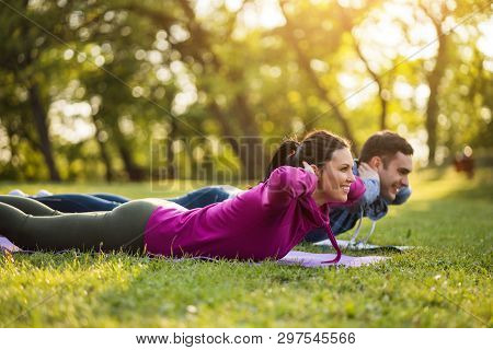Couple Is Exercising In Park. Exercise For Sciatica Recovery.