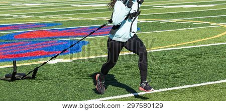 High School Girl Pulling A Sled With Twenty Five Pounds On It Across A Turf Field Wearing Black Span