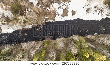 Aerial View Of A River In The Forest With Snow Along The Banks.
