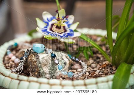 Jewelery Made Of Natural Stones Against The Backdrop Of Blossoming Pasiflora. Bracelets, Rings, Neck