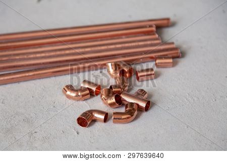 Closeup Many New Copper Dyne Pipesб Fittings On The Concrete Floor. Concept Installation, Replacemen