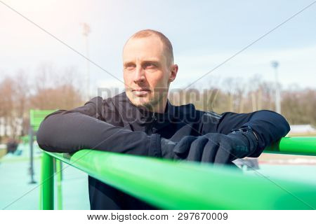 Photo of sportsman pulling up on green horizontal bar