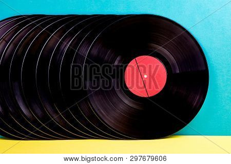 Many Black Colored Vinyl Discks Placed  In A  Line On Yellow And Blue Background.