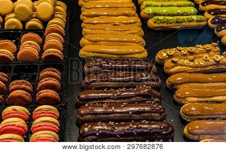 Many Colorful Makaroons And Chocolate And Caramel Eclair With Nuts And Cream On Display