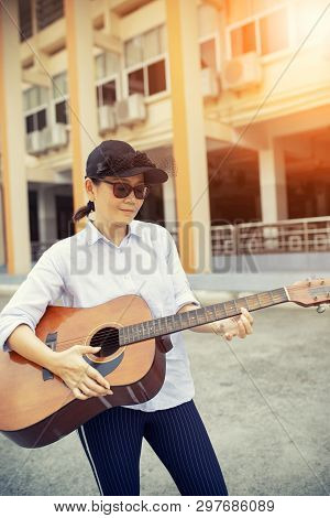 Woman Playing Acoustic Guitar On Street Side
