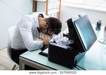 Tired Businessman Resting His Head In Front Of Paper Stuck In Printer