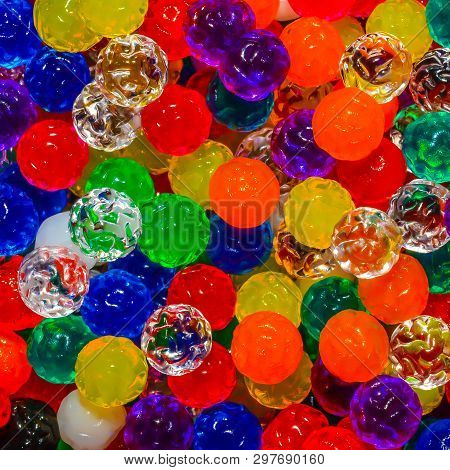 Close up background of tiny multicolored jelly-like beads with bumpy surfaces and textures.