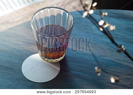 Transparent Glass With Tea And Beer Coaster On Wooden Table. 3d Rendering.