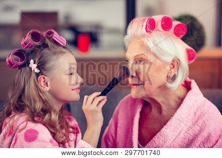 Girl Holding Brush And Putting Facepowder On Face Of Granny