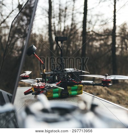 Fpv Drone Lies On The Table Near The Laptop And Control Panel. The Pilot Sets Up His Racing Drone Be