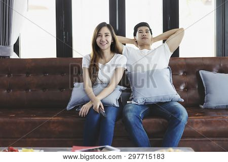 Happy Asian Young Couple Loving On The Couch Watching A Movie Together, Woman Holding Remote And Her