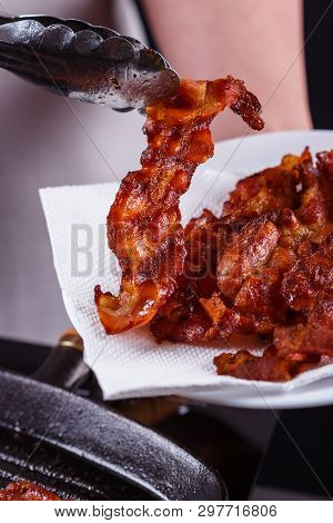 Young Woman In A Gray Apron Fries Bacon