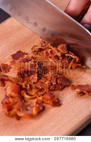 Young Woman In A Gray Apron Cuts Roasted Bacon