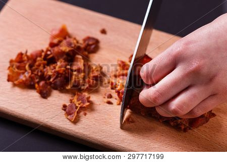 Young Woman In A Gray Apron Cuts Roasted Bacon