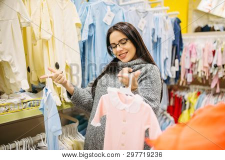 Woman choosing clothes in the store for newborns