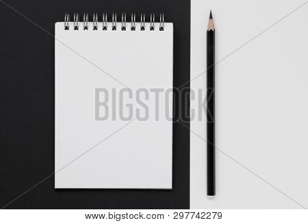Open Spiral Notebook And Black Pencil, On A Black And White Background