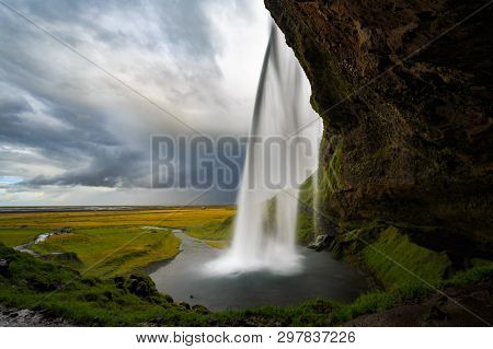 View From Behind The Seljalandsfoss Waterfall In Iceland.