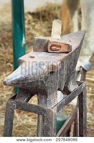 Old Anvil With Hammer On A Metal Stump