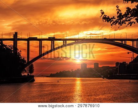 Silhouette of Arrabida Bridge against the sunset sky over the Duoro river, Porto, Portugal