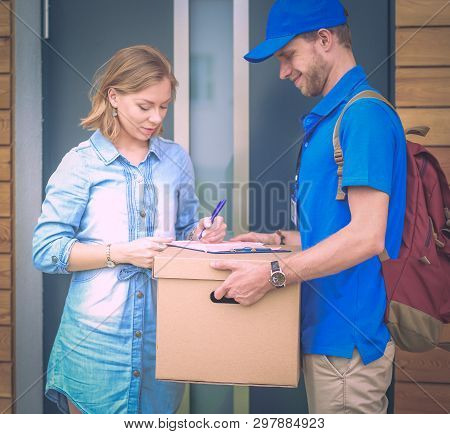 Smiling Delivery Man In Blue Uniform Delivering Parcel Box To Recipient - Courier Service Concept. S