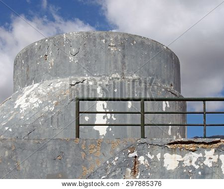 An Old Crumbling Concrete Military Bunker Type Structure With Rounded Windowless Surfaces And A Gree