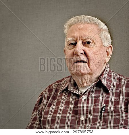 Senior Octogenarian Old Man In Plaid Shirt With Gray Background.