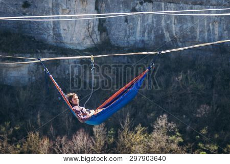 Man Hanging  In Hammock Above Mountain Valley Gap. Slack Line Contest.