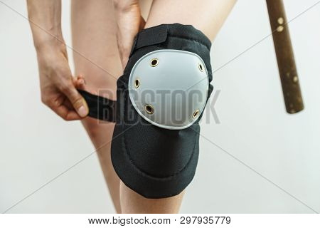 Unrecognizable Woman Wearing And Adjusting Her Safety Knee Protectors Pads. Safe Workwear During Con
