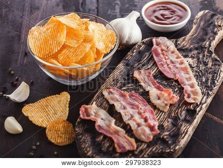 Potato Crisps With Backon Flavour With Grilled Bacon Rashers On Vintage Chopping Board With Garlic A