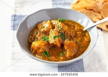Close Up Traditional Indian Butter Chicken Curry And Lemon Served With Chapati Bread On Grey Plate.