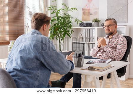 Senior Account Manager And Young Man During Job Interview In Small Firm