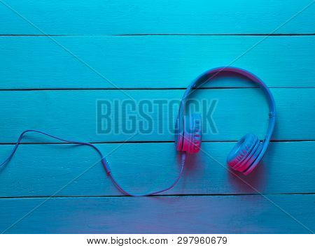 Headphones On Wooden Background. Retro Wave, Neon Light, Ultraviolet. Top View, Minimalism