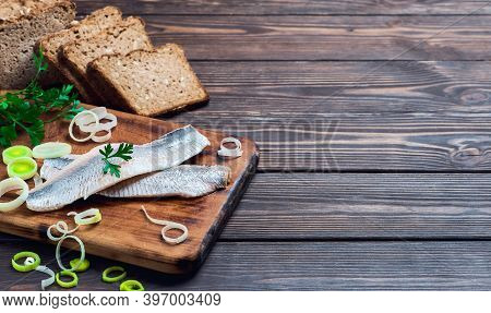 Herring Fillet With Parsley And Onions On A Cutting Board, Dark Wooden Background With Place For Tex