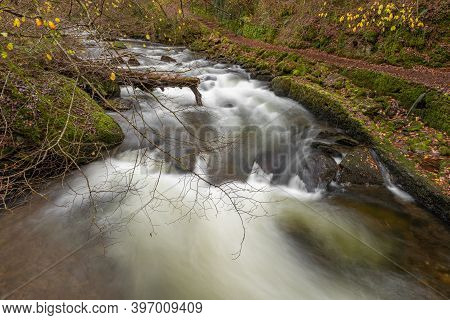 Long Exposure Of A Waterfall On The East Lyn River Flowing Through The Woods At Watersmeet In Exmoor