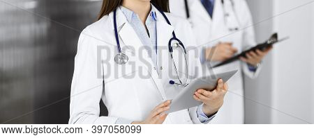Unknown Woman Doctor Iusing Tablet Computer In Her Hands, While Standing In Clinic. Medicine Concept