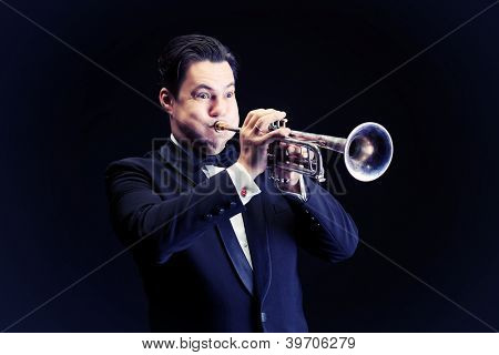 Retrato de um músico tocando a trombeta. Fundo preto.