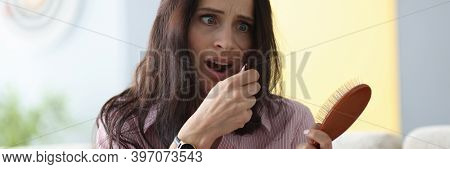 Frightened Woman Holds Comb In Her Hands And Looks At Her Hair. Split Ends Hair Treatment Concept