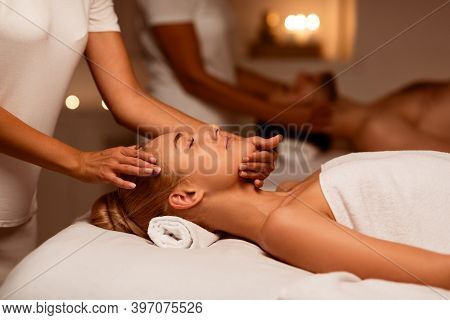 Couple Enjoying Relaxing Face Massage In Luxury Spa, Lying With Eyes Closed During Beauty Procedure.