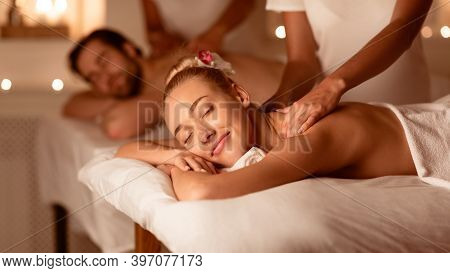 Husband And Wife Receiving Back Massage Relaxing Lying At Spa Center. Masseuses Massaging Backs Duri
